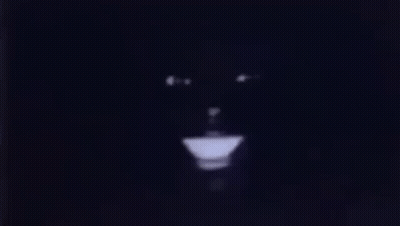 A Close Up Of A Person 'S Face In The Dark With A Light Coming Out Of It . GIF