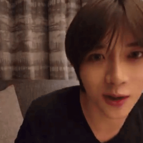 A Close Up Of A Person 'S Face With A Black Shirt On And A Curtain In The Background . GIF
