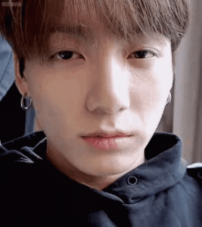 A Close Up Of A Person 'S Face With A Hoodie And Earrings . GIF
