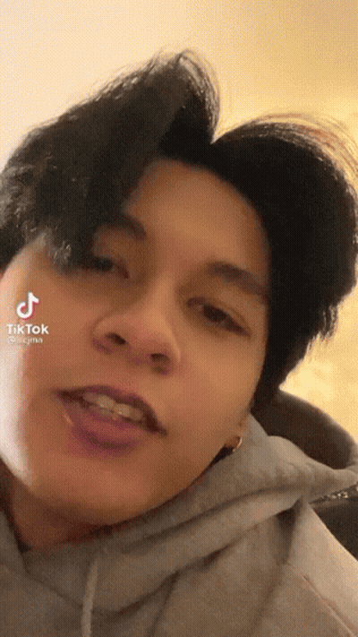 A Close Up Of A Person 'S Face With A Hoodie On And A Purple Haircut . GIF