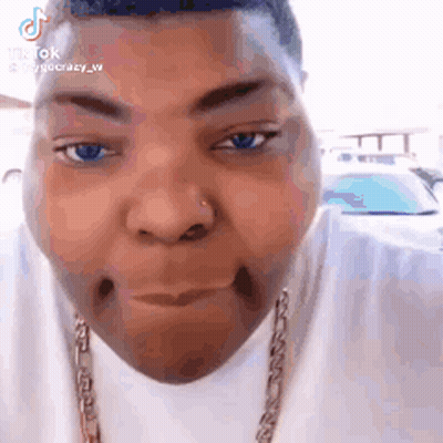 A Close Up Of A Person 'S Face With A Necklace Around Their Neck . GIF