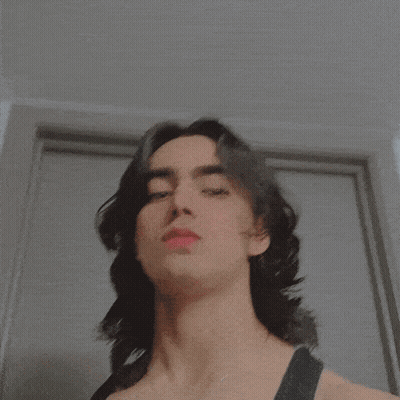 A Close Up Of A Person 'S Face With A Necklace That Says ' I ' On It GIF