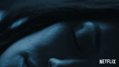 A Close Up Of A Person 'S Face With A Netflix Logo Behind It GIF