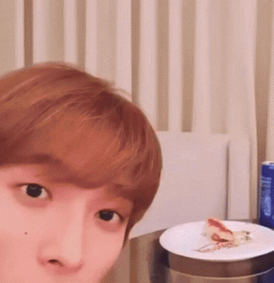 A Close Up Of A Person 'S Face With A Plate Of Food On A Table . GIF