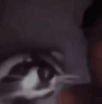 A Close Up Of A Person 'S Face With A Shadow Of A Cat 'S Eye Behind Them . GIF