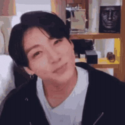 A Close Up Of A Person 'S Face With A Statue Of A Face In The Background . GIF