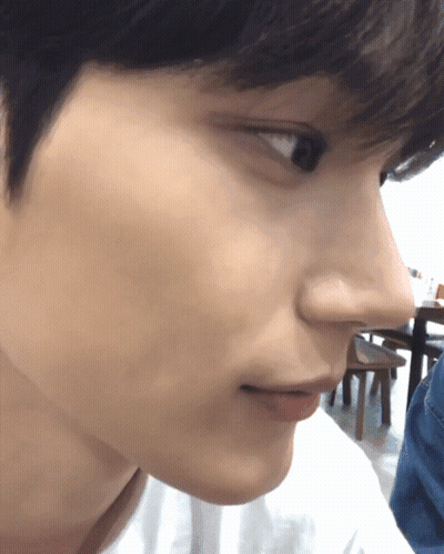 A Close Up Of A Person 'S Face With A Table And Chairs In The Background GIF