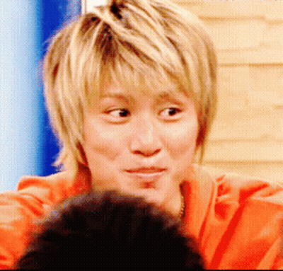 A Close Up Of A Person 'S Face With Blonde Hair And An Orange Shirt GIF