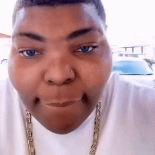 A Close Up Of A Person 'S Face With Blue Eyes And A Gold Chain Around Their Neck GIF