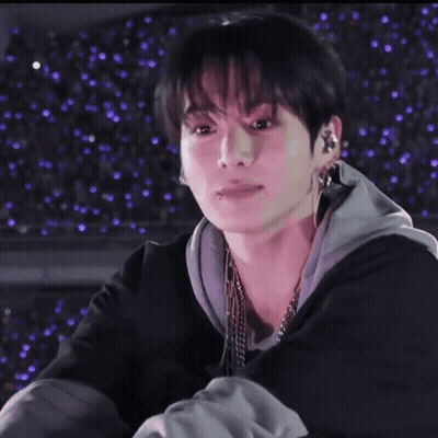 A Close Up Of A Person 'S Face With Purple Lights Behind Them . GIF