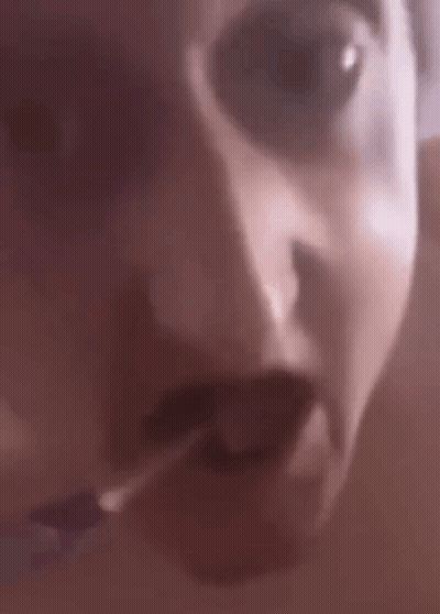 A Close Up Of A Person 'S Face With Their Mouth Open And A Cigarette In Their Mouth . GIF