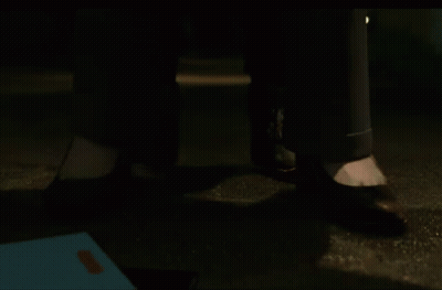 A Close Up Of A Person 'S Feet Standing On The Ground At Night . GIF