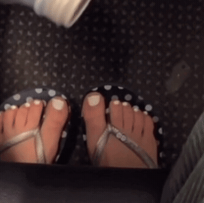 A Close Up Of A Person 'S Feet Wearing Flip Flops On A Carpet GIF