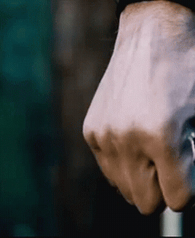 A Close Up Of A Person 'S Fist Holding A Cane In A Dark Room . GIF