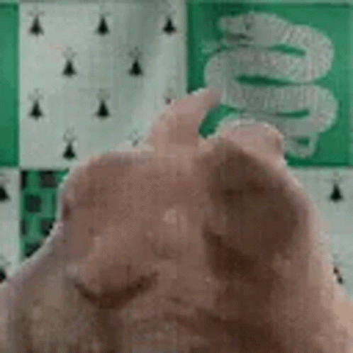 A Close Up Of A Person 'S Hand Giving A Thumbs Up In Front Of A Green And White Checkered Wall . GIF