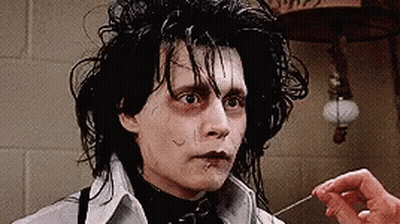 A Close Up Of A Person 'S Hand Holding A Needle To A Man 'S Face . GIF