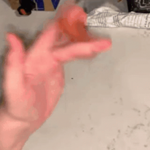 A Close Up Of A Person 'S Hand Holding A Red Object On A Table . GIF
