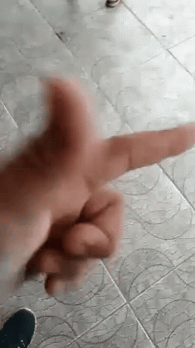 A Close Up Of A Person 'S Hand Making A Peace Sign On A Tile Floor . GIF