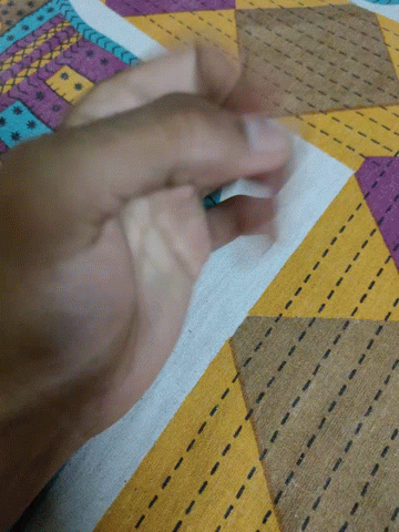 A Close Up Of A Person 'S Hand On A Colorful Fabric GIF