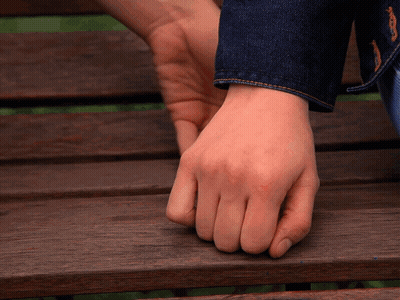 A Close Up Of A Person 'S Hand On A Wooden Bench GIF
