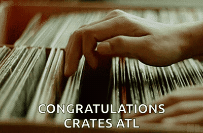 A Close Up Of A Person 'S Hand Picking A Record From A Shelf That Says Congratulations Crates GIF