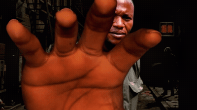 A Close Up Of A Person 'S Hand With A Man 'S Face In The Background GIF