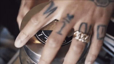 A Close Up Of A Person 'S Hand With Tattoos And A Ring GIF
