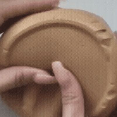 A Close Up Of A Person 'S Hands Holding A Brown Container . GIF