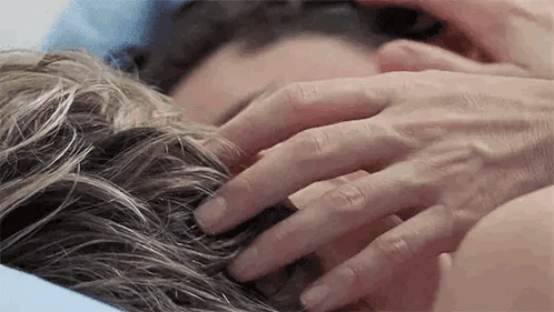 A Close Up Of A Person 'S Hands On A Woman 'S Hair . GIF