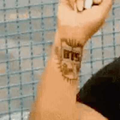 A Close Up Of A Person 'S Wrist With A Tattoo That Says Bts GIF