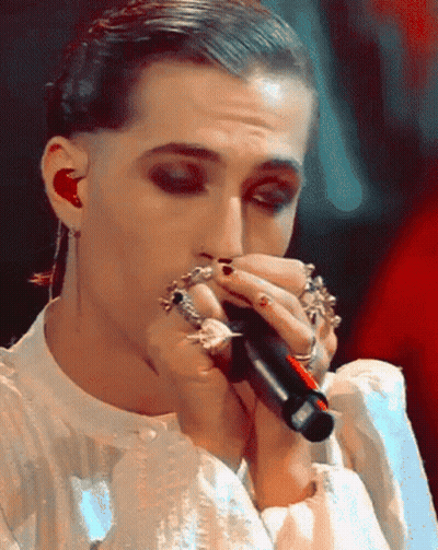 A Close Up Of A Person Singing Into A Microphone With Rings On Their Fingers GIF