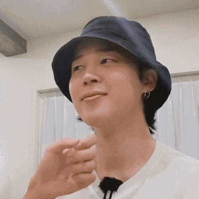 A Close Up Of A Person Wearing A Bucket Hat And Earrings . GIF