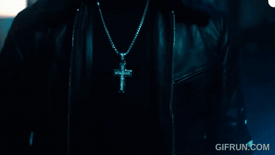 A Close Up Of A Person Wearing A Cross Necklace With Gifrun.com In The Corner GIF