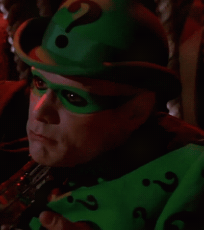 A Close Up Of A Person Wearing A Green Hat And Mask With A Question Mark . GIF
