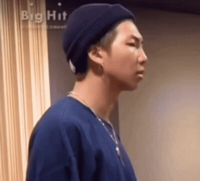 A Close Up Of A Person Wearing A Hat And A Necklace . GIF