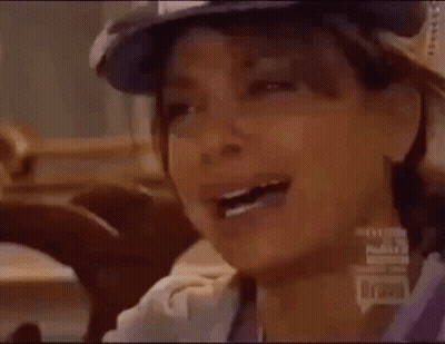 A Close Up Of A Person Wearing A Hat And A Purple Shirt . GIF