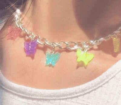 A Close Up Of A Person Wearing A Necklace With Colorful Butterflies And Stars . GIF