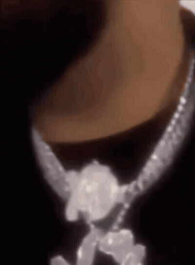 A Close Up Of A Person Wearing A Necklace With Diamonds On It GIF