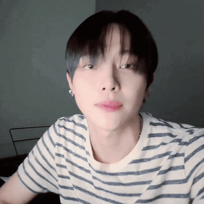 A Close Up Of A Person Wearing A Striped Shirt And Earrings GIF