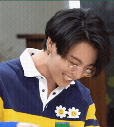 A Close Up Of A Person Wearing Glasses And A Sweater With A Smiley Face On It . GIF