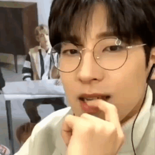 A Close Up Of A Person Wearing Glasses And Headphones Eating Something . GIF