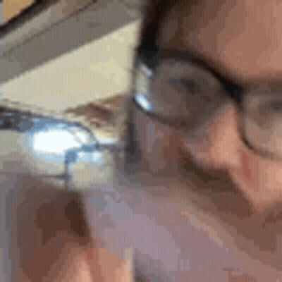 A Close Up Of A Person Wearing Glasses Talking On A Phone . GIF