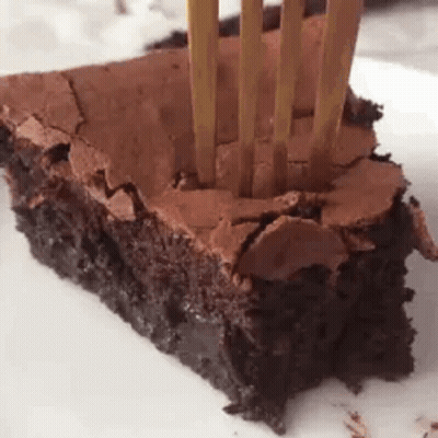 A Close Up Of A Piece Of Chocolate Brownie With A Fork Sticking Out Of It . GIF