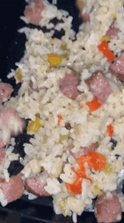 A Close Up Of A Plate Of Food With Rice , Sausage , And Peppers . GIF