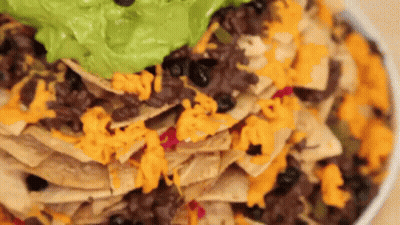A Close Up Of A Plate Of Nachos With Guacamole And Cheese . GIF