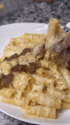 A Close Up Of A Plate Of Pasta With Cheese And Meat On It GIF