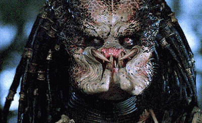 A Close Up Of A Predator 'S Face With Dreadlocks And Sharp Teeth GIF