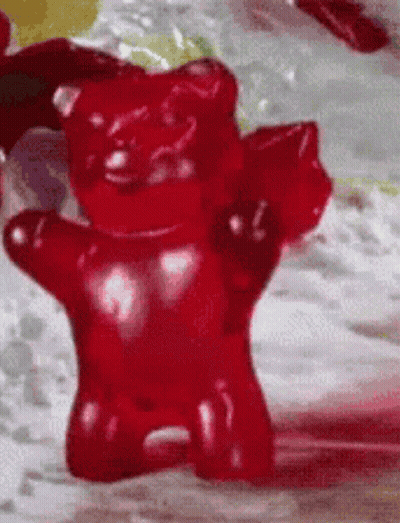 A Close Up Of A Red Gummy Bear On A Table GIF