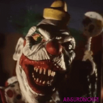 A Close Up Of A Scary Clown Holding A Lollipop And Wearing A Yellow Hat . GIF