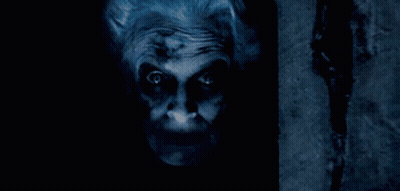 A Close Up Of A Scary Clown 'S Face With A Dark Background GIF